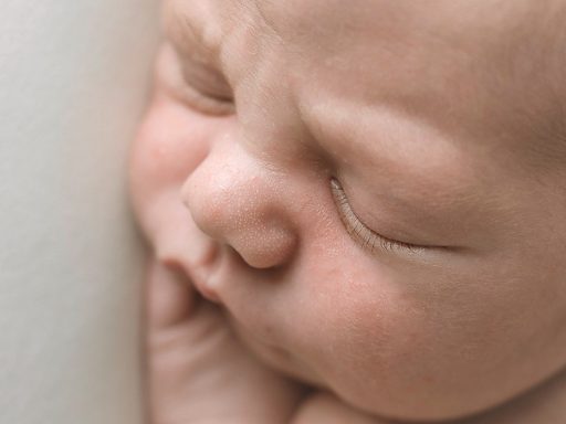 Bebé dormido, con rostro tierno y manos sobre la mejilla.