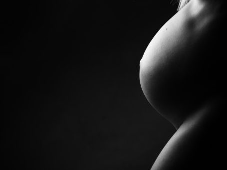 Contorno suave de un abdomen en blanco y negro con luz tenue.